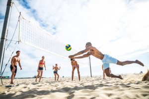 Man diving for ball during sand volleyball game with friends (1)