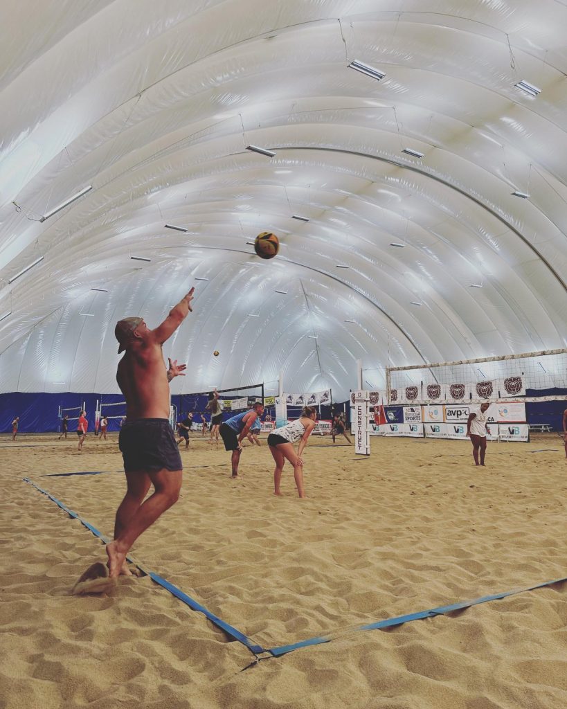 Player hitting ball on indoor sand volleyball court