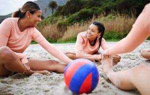 Women stretching on sand volleyball court