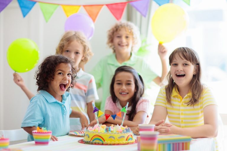 Children celebrate with a colorful cake and gifts