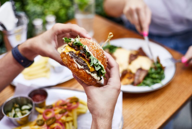 Close-up of a male's hands holding a delicious fresh burger