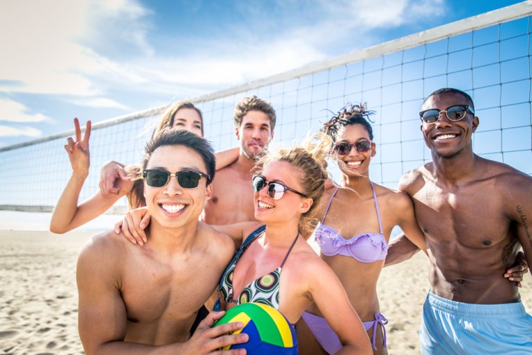 Group of friends posing for a photo on a beach volleyball court