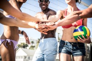 Group of friends stacking hands before a beach volleyball game